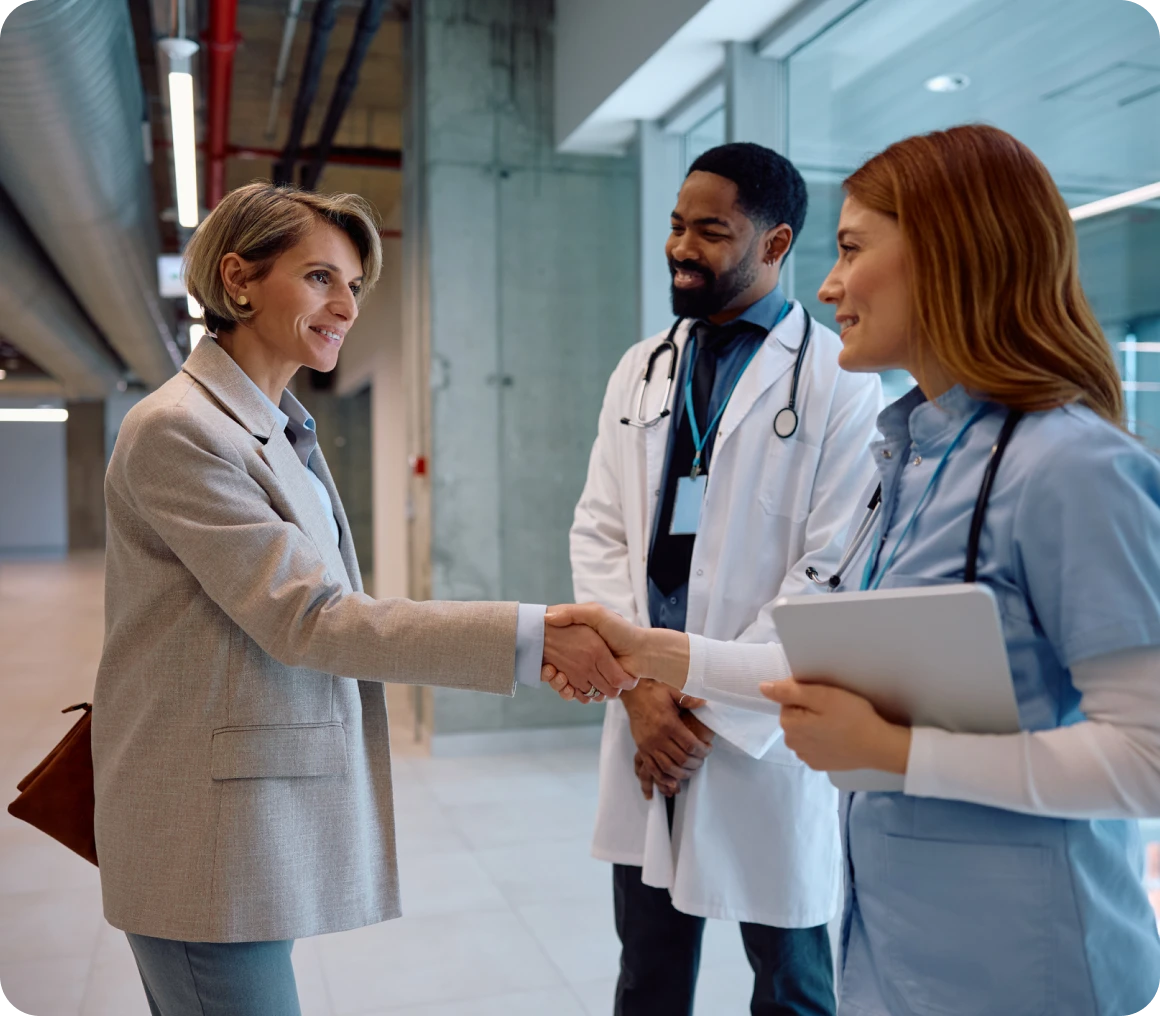 Doctors greeting woman in hospital hallway